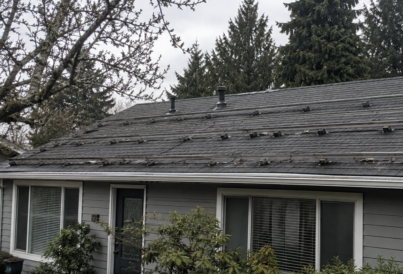 Solar panel mount hardware and satellite dish penetrations on an asphalt shingle roof in Kirkland, WA — Real Great Roofing mount removal and roof patching service